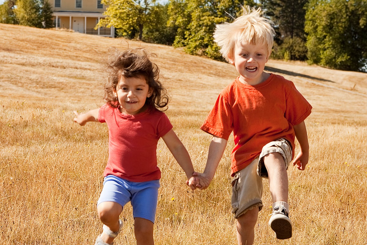 Two kids skip through field