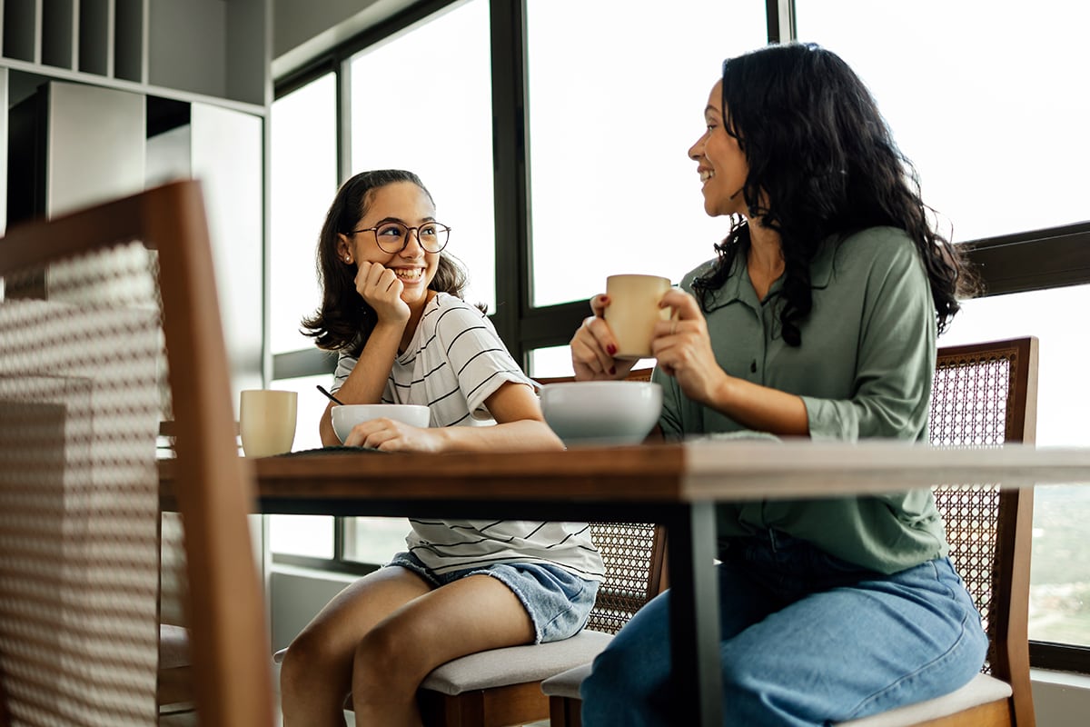 Woman drinks coffee and chats with young girl