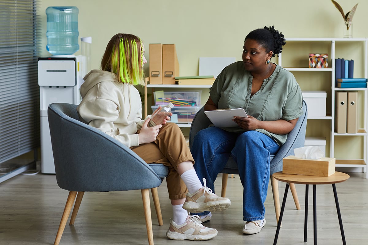 Teenager with green hair speaks with social worker