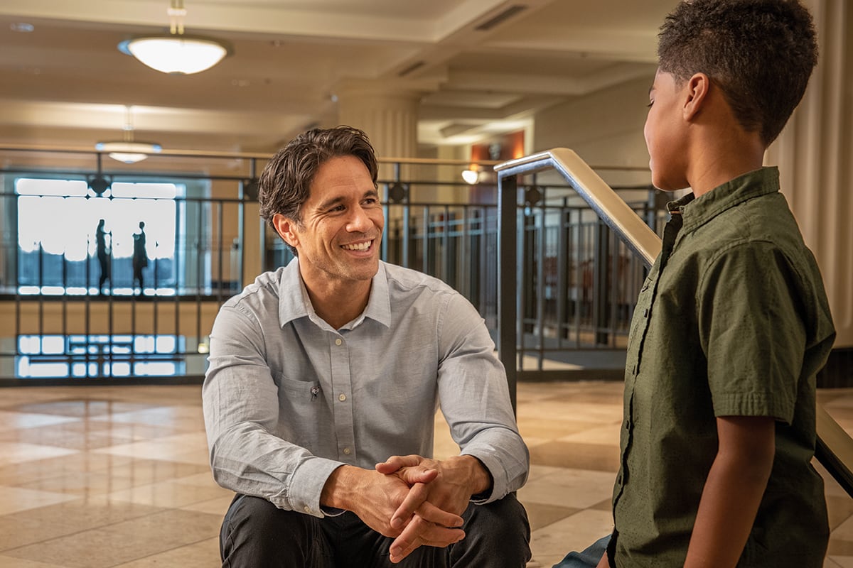 Man looks up at child while sitting on stairs